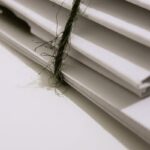 Pile of white envelopes tied with a green string, showcasing a minimalist design.